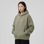 Blank heavyweight oversized hoodie in olive green, featuring a front pocket and a relaxed fit worn by a model.