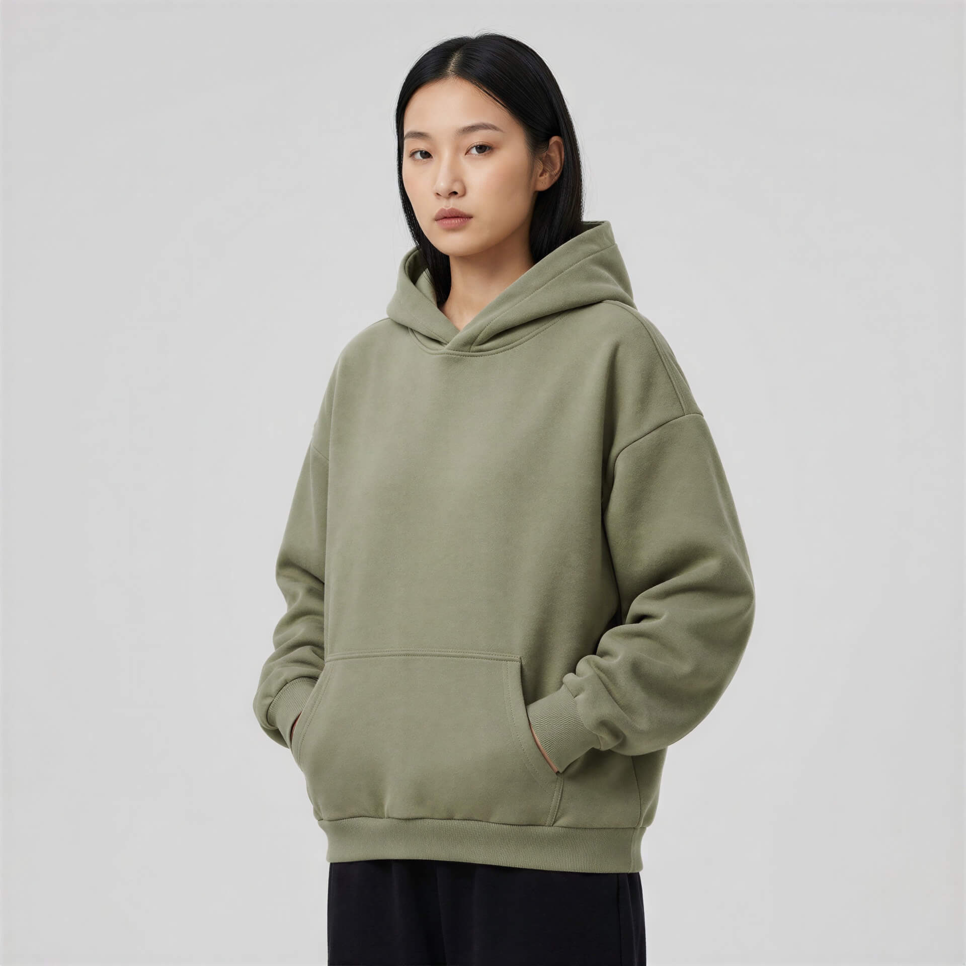 Blank heavyweight oversized hoodie in olive green, featuring a front pocket and a relaxed fit worn by a model.