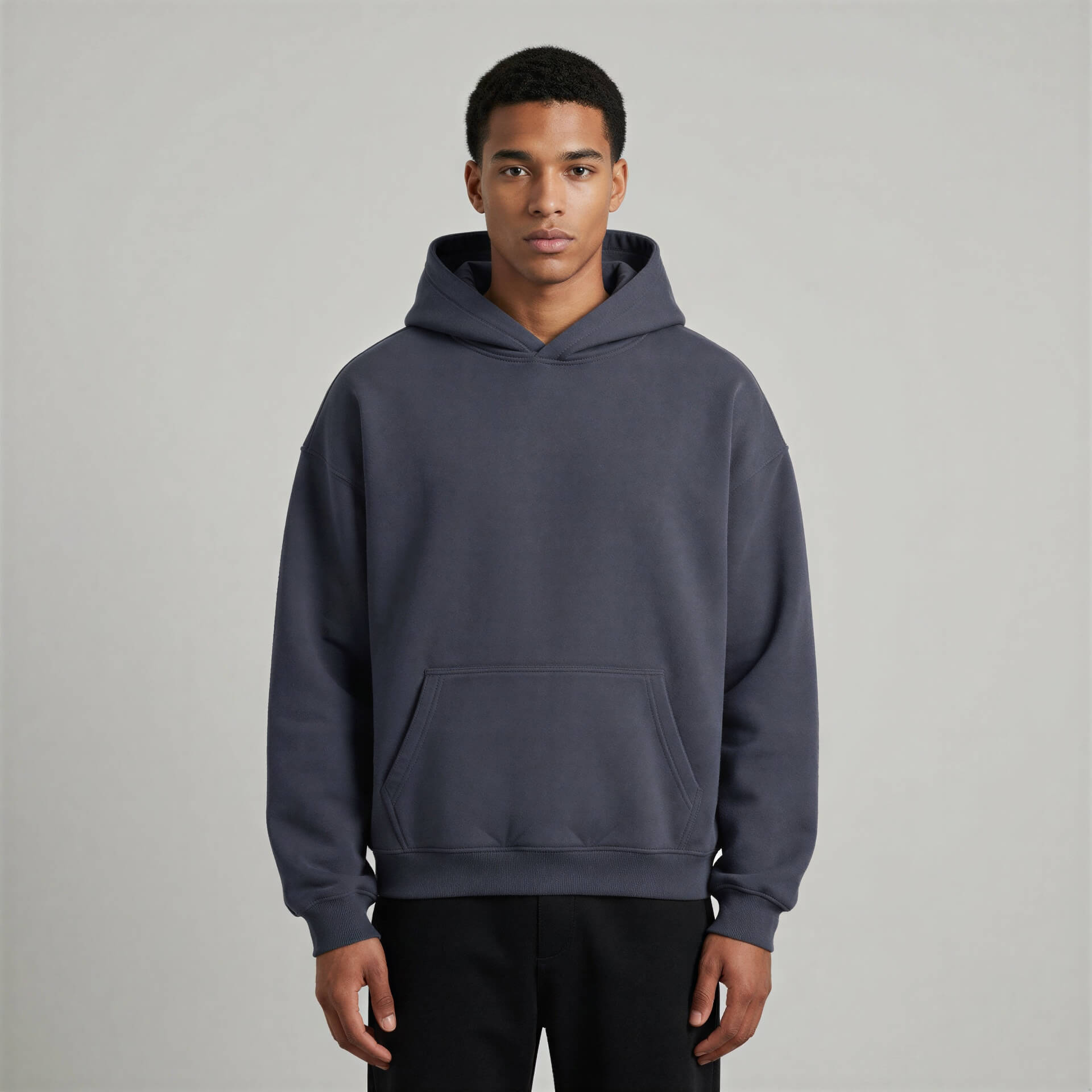 Blank heavyweight oversized hoodie in dark gray, featuring a front pocket and a spacious hood, worn by a model.
