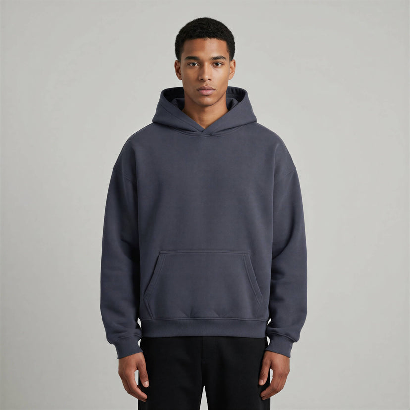 Blank heavyweight oversized hoodie in dark gray, featuring a front pocket and a spacious hood, worn by a model.