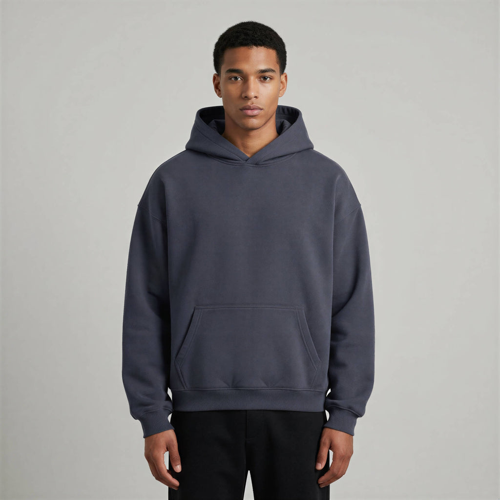 Blank heavyweight oversized hoodie in dark gray, featuring a front pocket and a spacious hood, worn by a model.