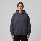 Heavyweight oversized hoodie in dark gray with a front pocket and adjustable drawstring hood, worn by a model.