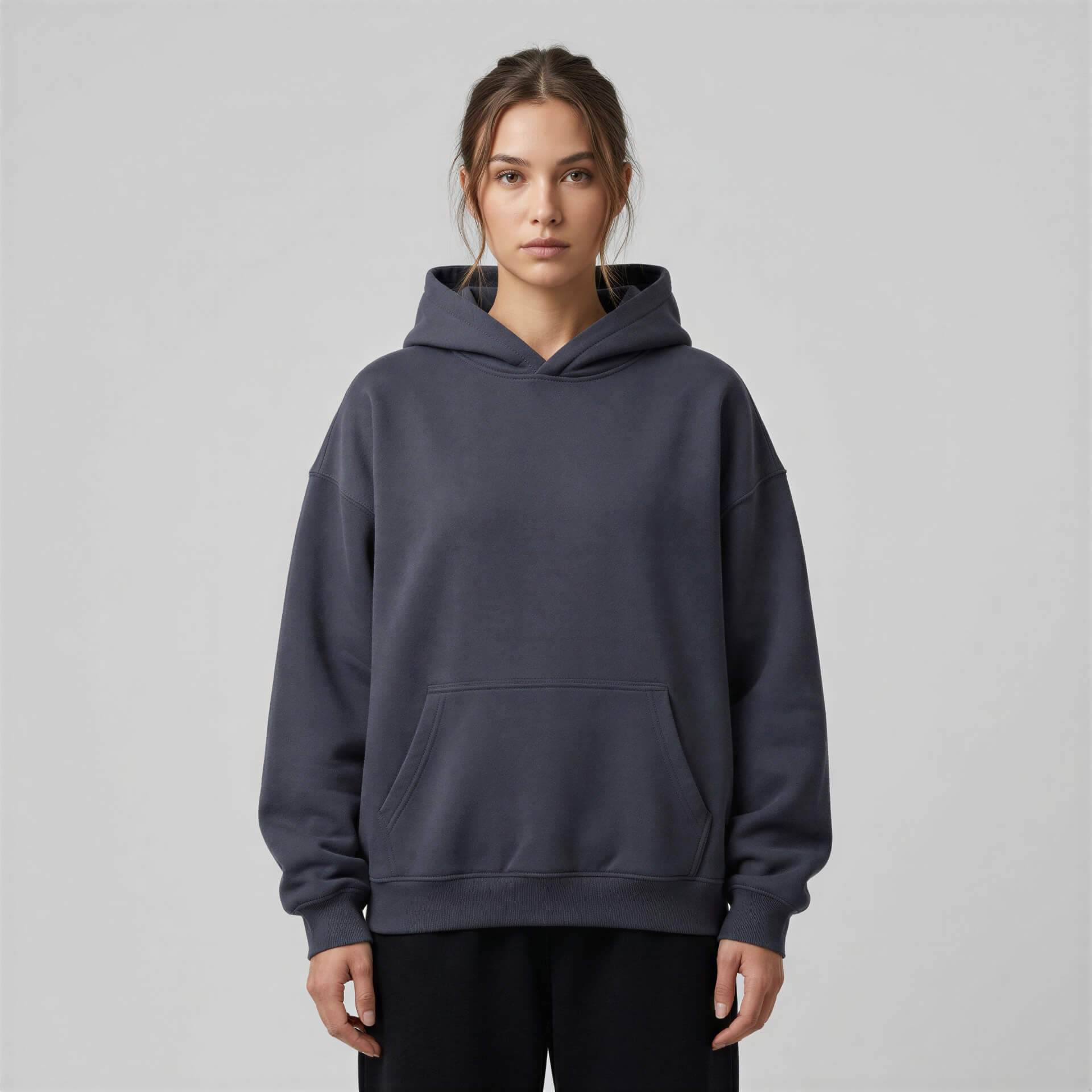 Heavyweight oversized hoodie in dark gray with a front pocket and adjustable drawstring hood, worn by a model.