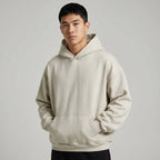Blank heavyweight oversized hoodie in light beige, featuring a front pocket and adjustable drawstring hood.