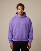 Heavyweight oversized hoodie in purple, featuring a front pocket and drawstring hood, worn by a model against a neutral ba...