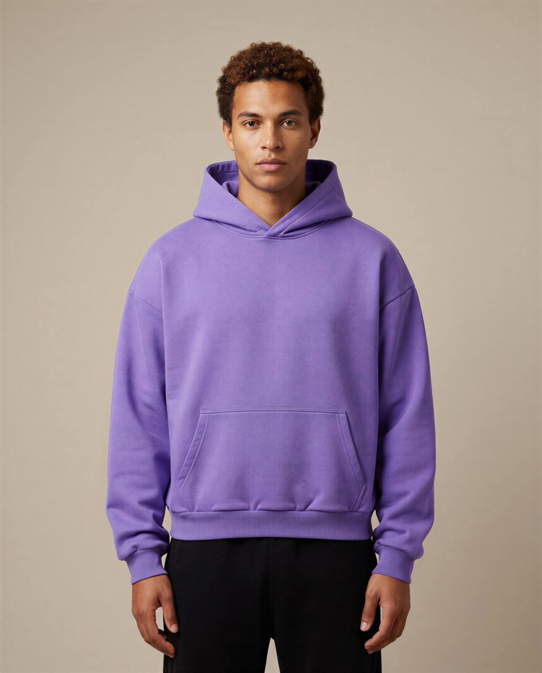 Heavyweight oversized hoodie in purple, featuring a front pocket and drawstring hood, worn by a model against a neutral ba...